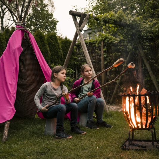 GIRLS BY CAMPFIRE COOKING BREAD ON STICKS